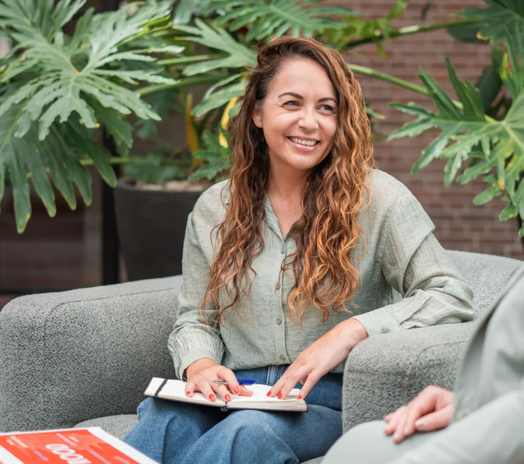 Vrouwelijke coach in gesprek met cliënt in groene en ontspannen omgeving, geassocieerd met Coaching2Do en Meral Akar voor Outplacement en Spoor 2 Begeleiding.