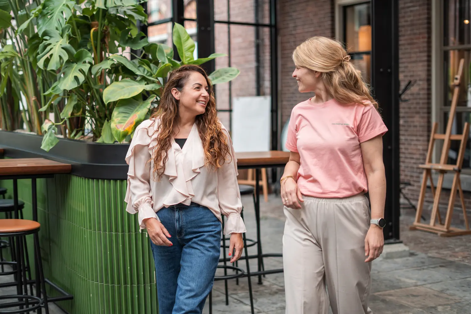 Vriendelijke informele ontmoeting tussen twee vrouwen in een groene stedelijke omgeving, verbonden aan Coaching2Do, Meral Akar, Outplacement en Spoor 2 Begeleiding.