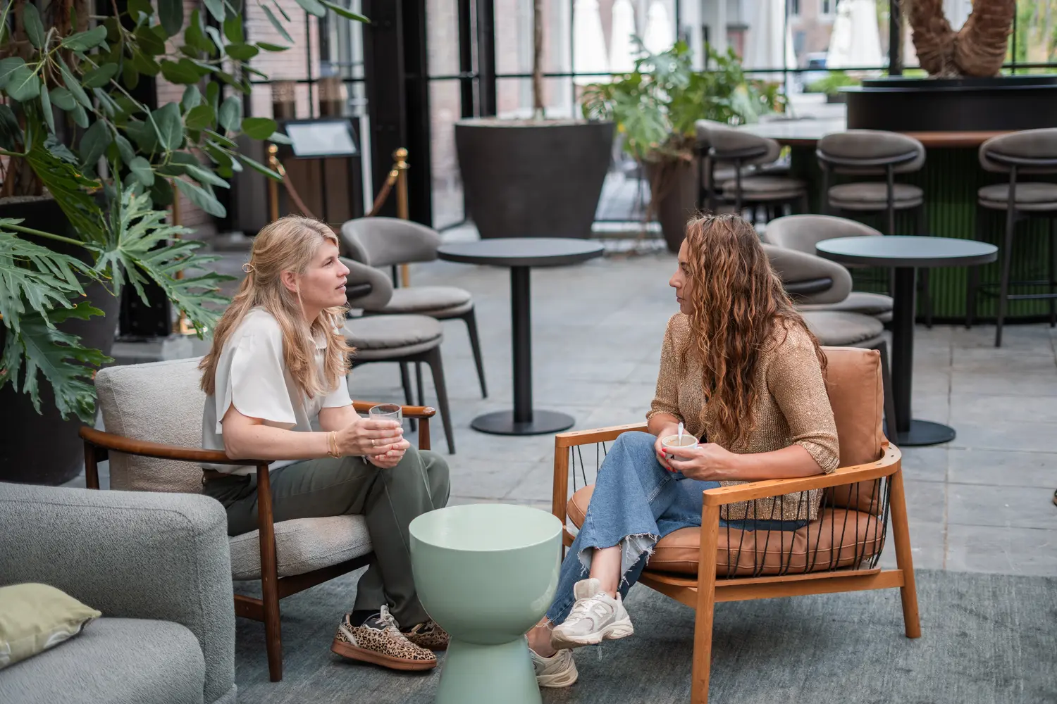 Coaching gesprek tussen twee vrouwen in een moderne, groene ruimte.