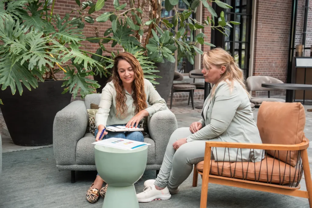 Professioneel gesprek tussen twee vrouwen in een ontspannen setting, gefocust op outplacement en Spoor 2 begeleiding bij Coaching2Do.