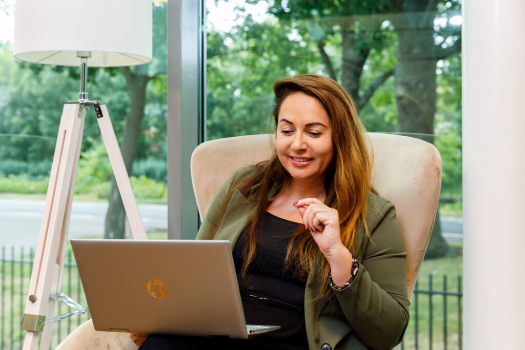 Meral Akar vrouw werkt geconcentreerd op een laptop in een moderne thuiswerkplek met groene omgeving.